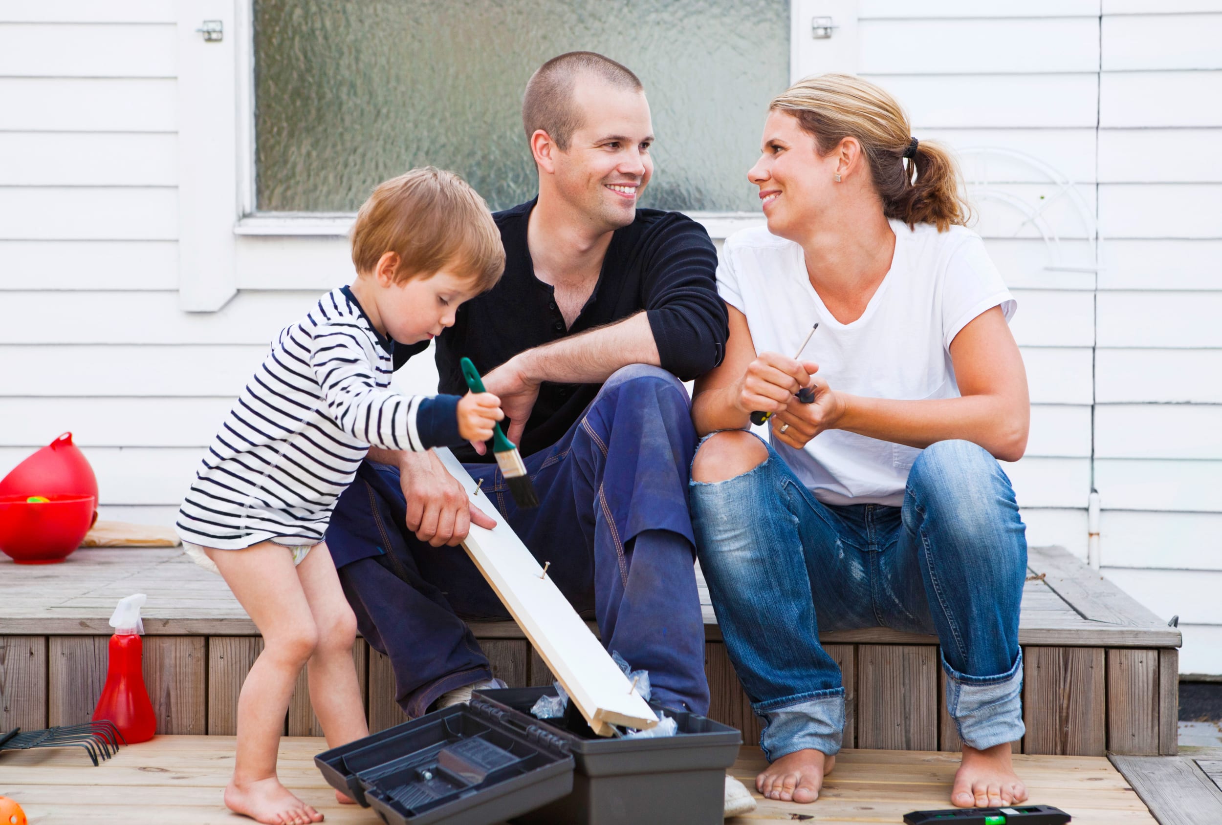 glad familie som sitter utenfor huset sitt